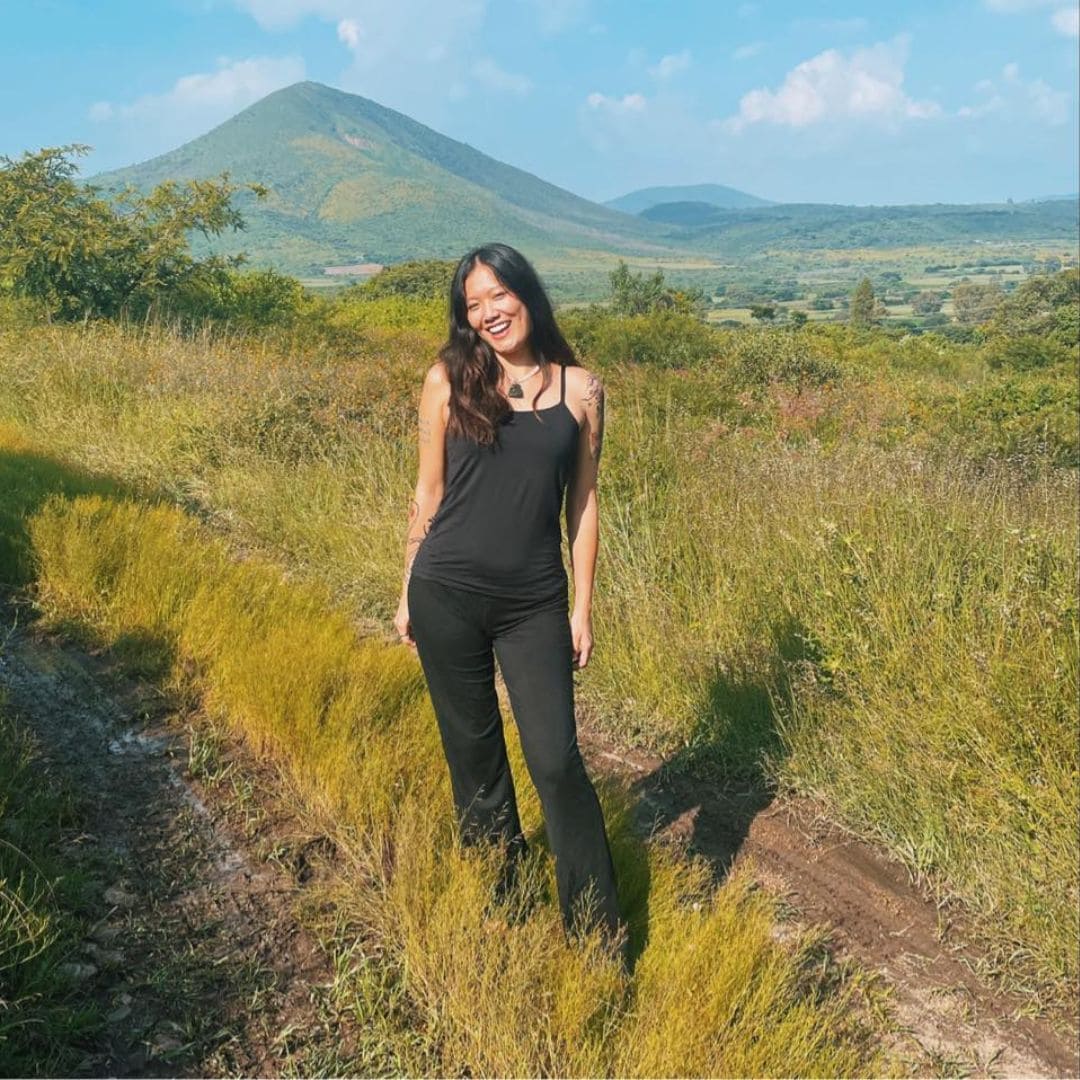 Woman standing on a dirt path with a mountain in the background