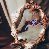 Person wearing a white blouse with long sleeves in front of an ornate mirror.